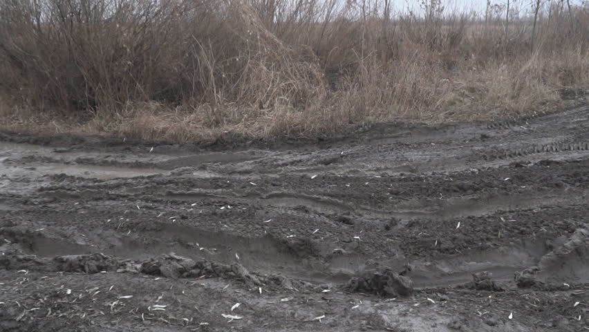 A dirty impassable country road with deep ruts. Soft focus. Camera panning