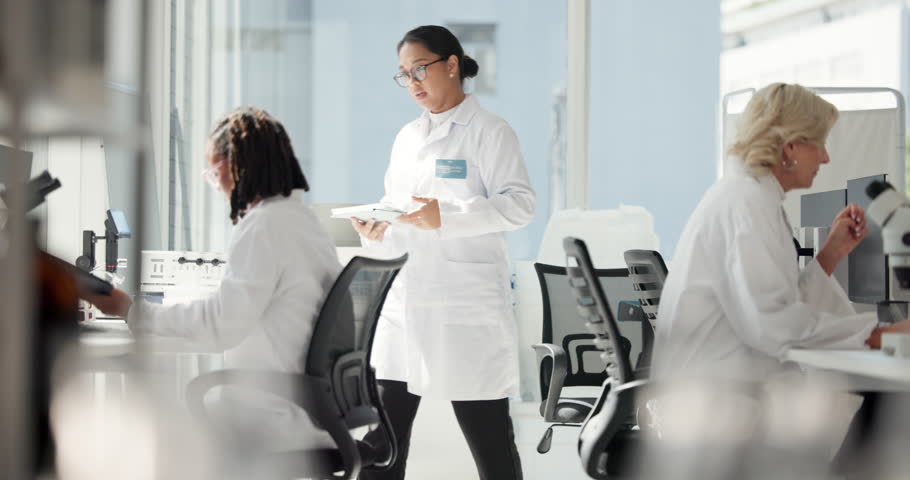 Women, tablet and discussion in lab, research and review for progress, drugs and team at pharmaceutical company. People, science and digital touchscreen for medical project with vaccine development