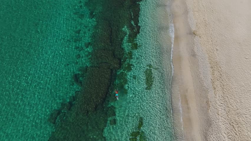 Aerial Video of a Man Swimming in the Calm Blue Sea, Moving Smoothly Through the Water Under a Clear Sky