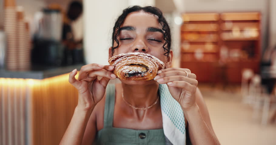 Woman, croissant and eating pastry in coffee shop, hungry and bite of delicious snack in bistro. Sweet food, female person and bakery customer with confectionery craving, meal and local restaurant