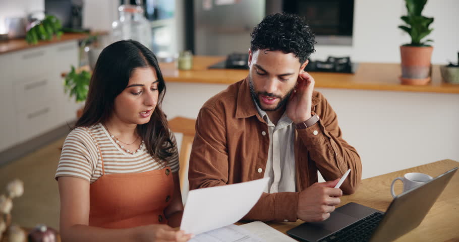 Couple, laptop and discussion with documents for finance, bills and planning with taxes in home kitchen. Computer, man and woman with stress for budget, debt and asset management for mortgage payment