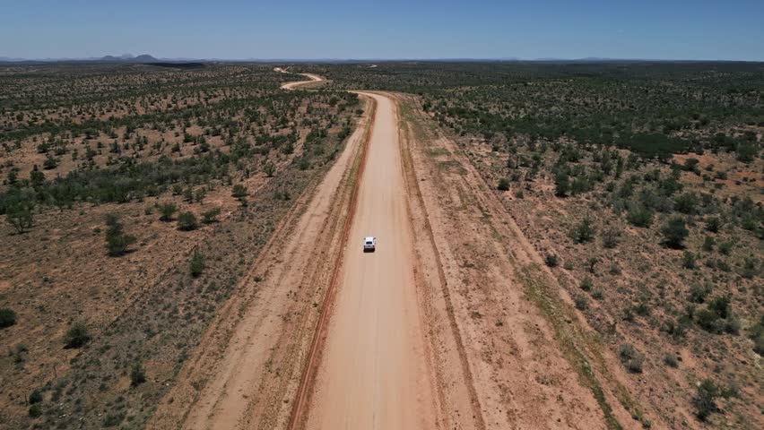 Car travels Windhoek-Sesriem desert road to distant horizon Namibia DRONE