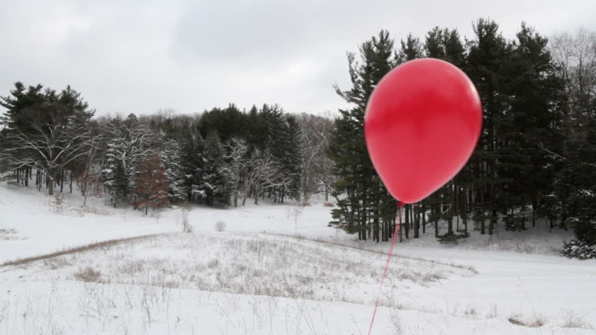 Red helium balloon in a snow landscape. Dolly shot.