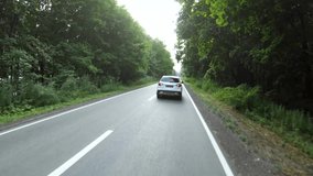 Aerial shot of car riding through forest rural road. White SUV driving at empty country route near wood on summer day. Follow to auto moving during journey or trip. Scenic landscape way. Slow motion - Powered by Shutterstock - Get 15% off with code: PIKWIZARD15