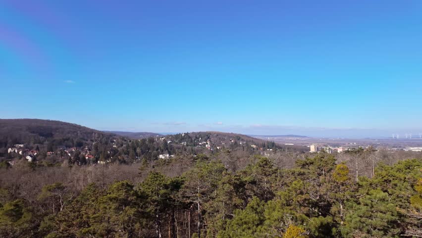 Sopron suburb with houses standing out from the trees in the distance on the hillside in nature on a sunny day in Hungary.
