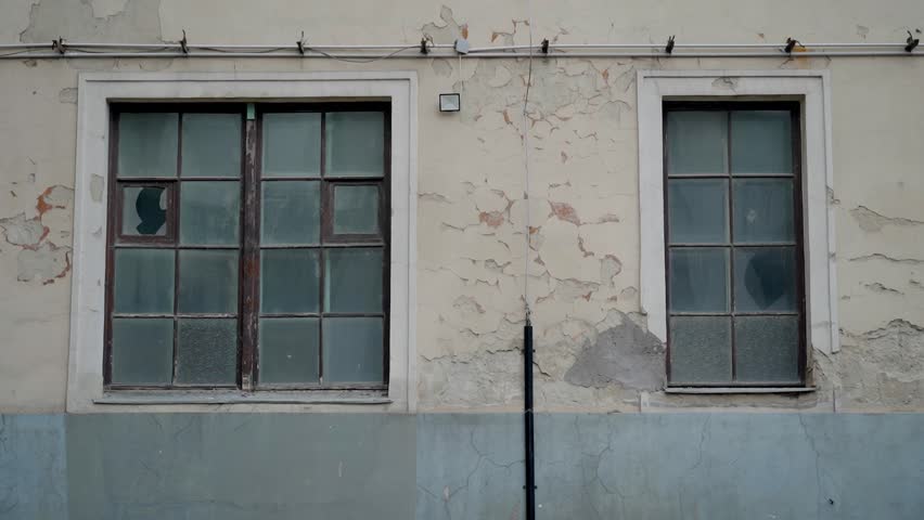 Cracked windows and peeling paint on an old wall