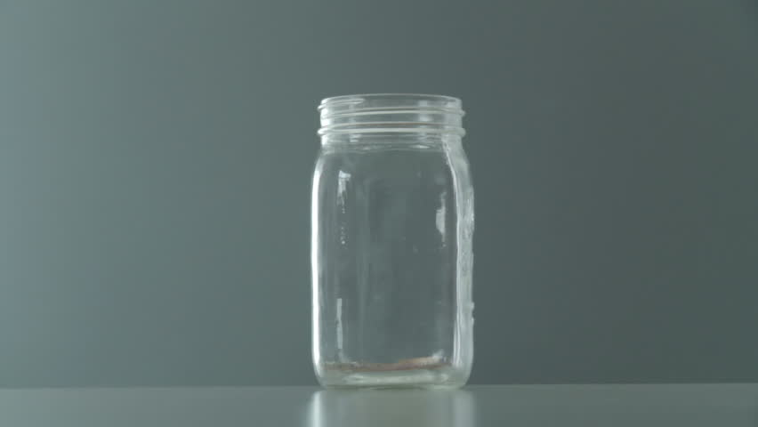 Jar gets filled with one dollar and five dollar bills. Clip starts at normal