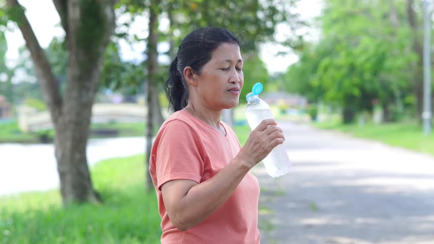 Lifestyle Health care. Footage Senior woman holding water bottle drink. Healthy beverage. Video People elderly holding water bottles, with natural environment background, fresh refreshing