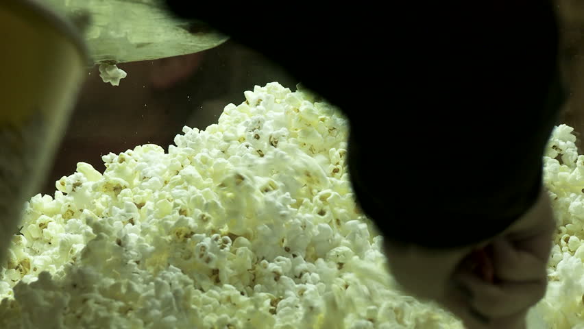 Close view of theater popcorn being served into a cardboard bucket.