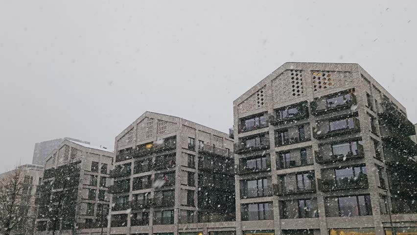 Modern residential buildings in Eilandje, Antwerp, during heavy snowfall, highlighting luxury design, large windows and urban winter ambiance