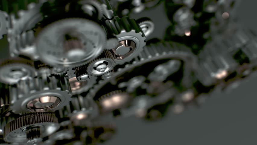 Rotating cogs of different materials and sizes interlock precisely. A metaphor for cooperation, teamwork, and the efficiency of a well-structured organization.