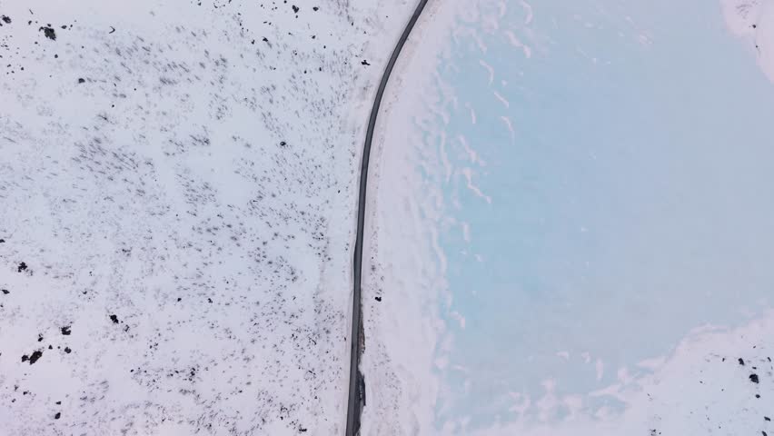 Snowy norwegian landscape, road along frozen lake and icy mountains, aerial view