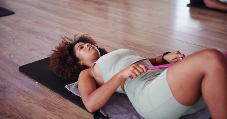 Resistance band, stretching and fitness with woman in class for workout, health and pilates studio. Exercise, wellness and warm up with person on yoga mat on gym floor for leg muscle, ready and start