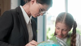 Teacher tutor woman female and Caucasian little girl child school kid learner pupil student schoolgirl learning globe studying geography magnifying glass exploring world map inside classroom education - Powered by Shutterstock - Get 15% off with code: PIKWIZARD15