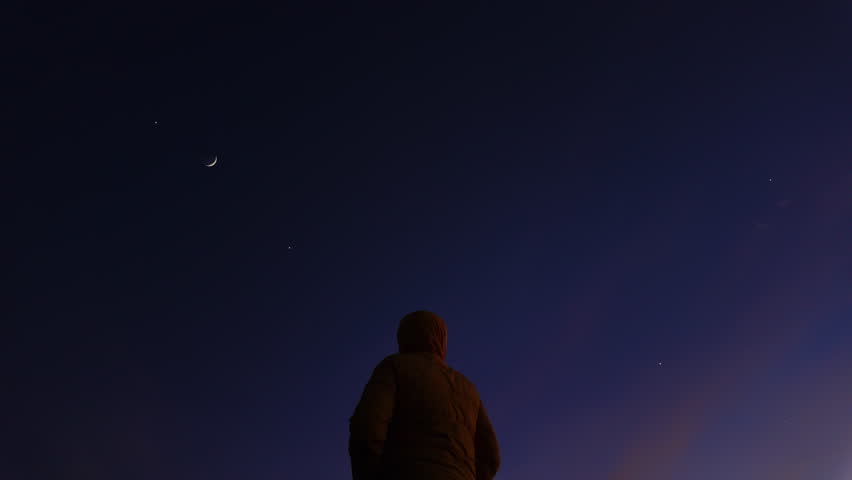 Silhouette of a man observing Milky Way stars, Moon and planets  from a countryside location..