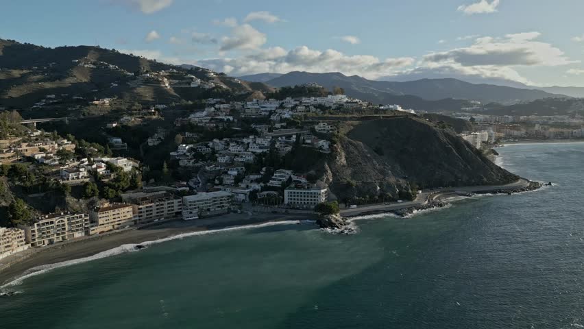 A captivating aerial view of the stunning Almunecar coast in Spain. The drone captures the scenic coastline with its beaches, rocky formations, and picturesque residential areas