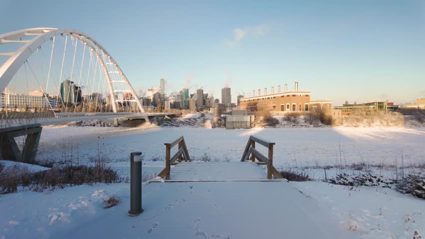 Downtown Edmonton, viewed from the Walterdale Bridge, showcasing Highrise buildings, a snowy river valley, and the cold beauty of the city