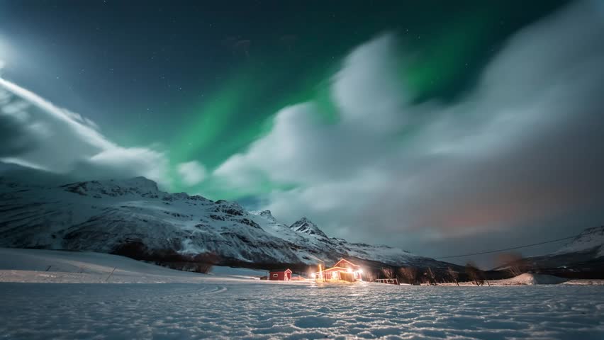Snowy Tromsø fjords at night with glowing cabin, moving clouds, and aurora borealis