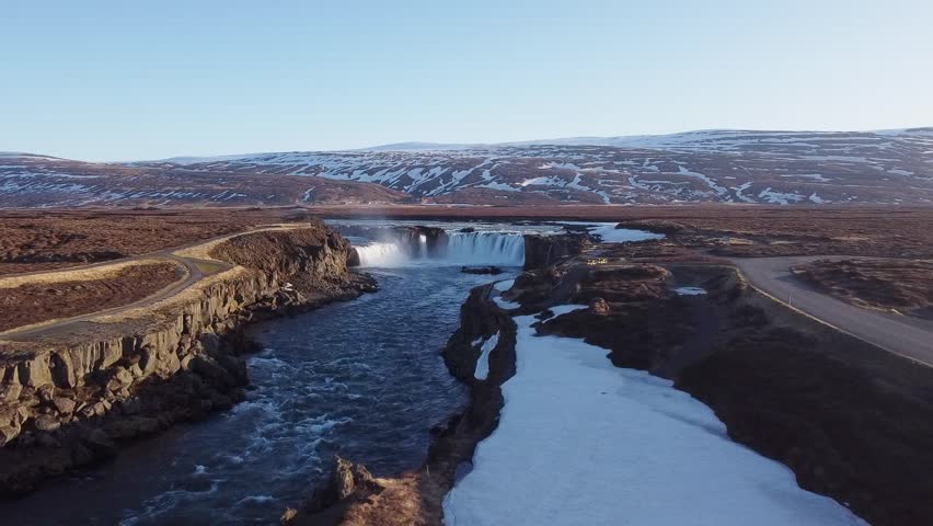 Powerful Goðafoss waterfall flowing between snow-covered cliffs, rocks, Iceland