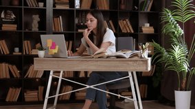 Beautiful student working on her school thesis on a laptop. Smart young woman sitting behind a desk studying an online course in an empty public library with modern design - Powered by Shutterstock - Get 15% off with code: PIKWIZARD15