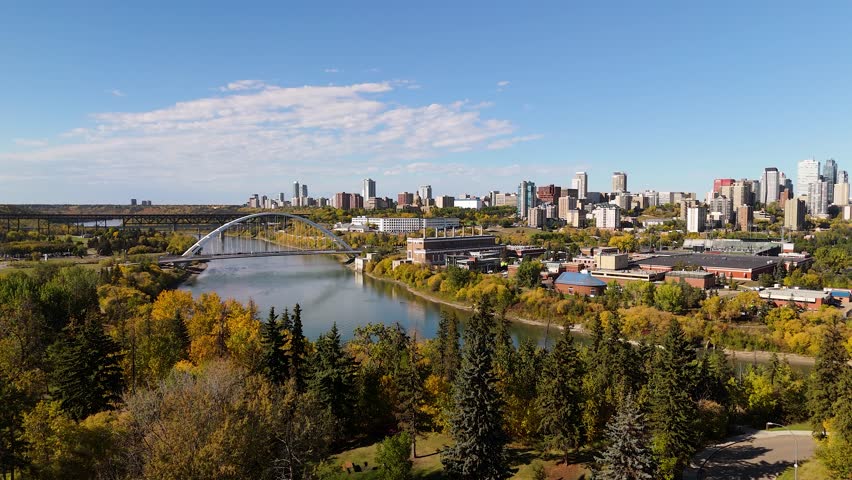 Ascending above trees in autumn revealing downtown Edmonton City