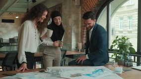 Multiethnic designers engineers architects business coworkers Caucasian Muslim women Indian man talk discuss plan architecture blueprints on table friendly conversation in office drink coffee teamwork - Powered by Shutterstock - Get 15% off with code: PIKWIZARD15