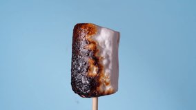 Marshmallow on Stick Burning, Covered with Black Crust, Sugar Bubbling and Smoking. Close-Up Roasting Candy on a Blue Background - Powered by Shutterstock - Get 15% off with code: PIKWIZARD15