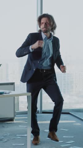 A man in a suit dances joyfully in an office, showcasing success