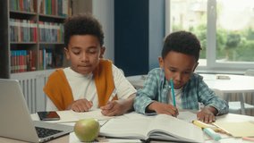 African American little boys children siblings kids schoolboys pupils students write studying together at desk elementary online school education laptop internet teacher video call computer e-learning - Powered by Shutterstock - Get 15% off with code: PIKWIZARD15