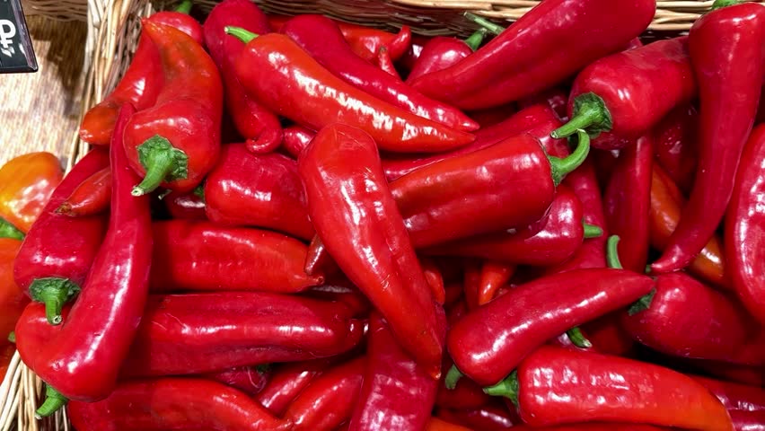 Vibrant red bell peppers are abundant in a market basket, showcasing their freshness and vivid color. Close-up.