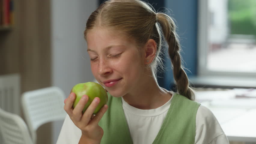 Caucasian girl teenager studying at school cute pretty kid child smiling daughter pupil schoolgirl student holding apple snack lunch education school learner smell fruit healthy vitamin food nutrition