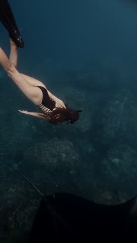 Girl freediver snorkel with Majestic black manta ray on Gili island corals, accompanied by remora fish that clings to its underside. Discover beauty of underwater life in this stunning marine habitat
