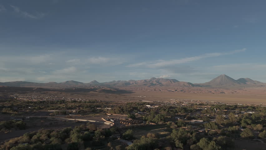 Sideways flying drone shot above San Pedro de Atacama Chile South America on a blue but cloudy day with mountains in the background LOG