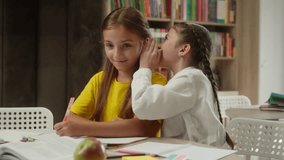 Caucasian little funny kids children friends talking in school classroom studying together laughing girls tell secret whisper gossip have fun conversation schoolgirls pupils students education indoors - Powered by Shutterstock - Get 15% off with code: PIKWIZARD15