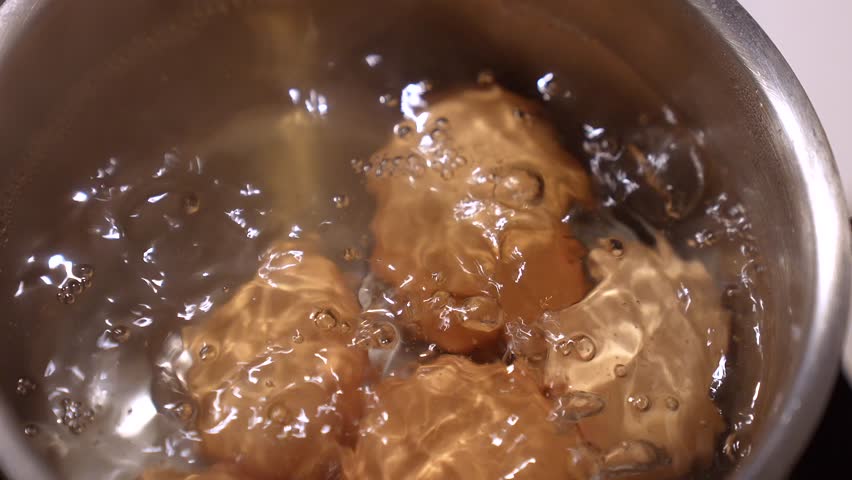 Boiling Organic eggs background. Healthy and protein ingredients concept. Farm produced natural eggs boiling in hot water with bubbles