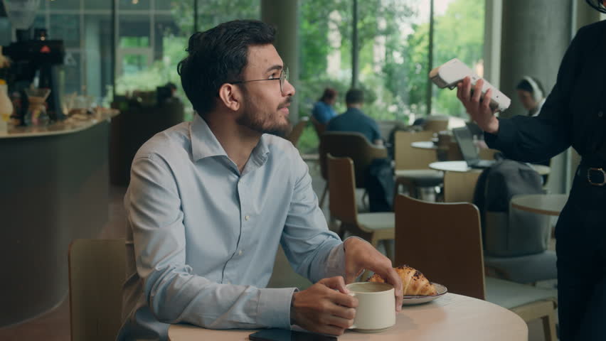 Waiter serving visitor in cafe Indian man guy male customer buyer client businessman coffee pay smartphone wifi scan contactless NFC payment online technology mobile phone credit card bank terminal