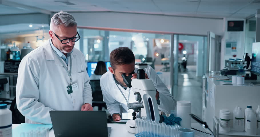 Men, scientist and microscope with tablet in lab for research, studying bacteria and medical results. People, biotechnology and high five of experiment success, testing goal and solution for vaccine