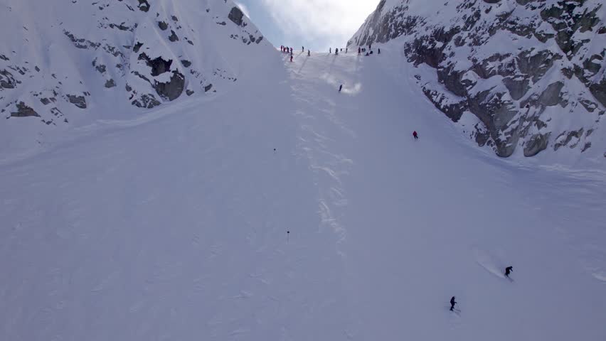 Aerial view of Whistler Mountain peak, downhill skiers, sunny snow covered peak, ski resort. 4K 24FPS