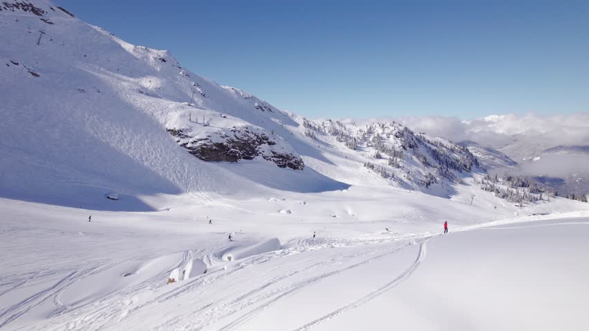 Downhill skiers with mountain vista, aerial footage, ski mountain, sunny day, winter, ski hill, Whistler BC. 5.4K 24FPS