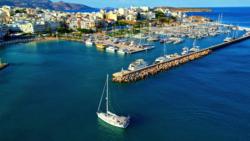 Aerial establishing view at Agios Nikolaos, City in Crete, Greece, ships sailing marine coastal landscape