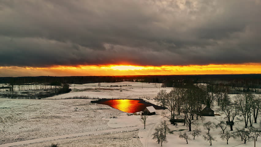 A serene winter sunset over a snowy landscape, reflecting on a frozen pond