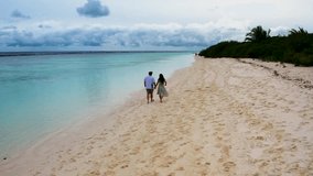 Aerial shot of a couple walking and dancing romantically on the white sandy beach of an island in the Maldives atoll sunset. Leisurely, romantic, poetic, touching, like being in heaven. - Powered by Shutterstock - Get 15% off with code: PIKWIZARD15