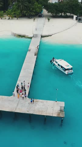 Aerial shot of the Maldives Fulidhoo inhabited island with sapphire waters and white speedboats picking up tourists at the T-shaped pier