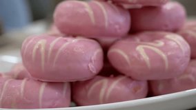 A plate of pink donuts with white stripes, part of a dessert display. Soft focus suggests a festive occasion. Enticing and delicious. - Powered by Shutterstock - Get 15% off with code: PIKWIZARD15
