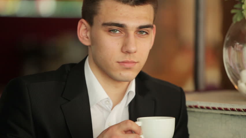 Close portrait of a businessman with a cup of coffee in the cafe. He looking at