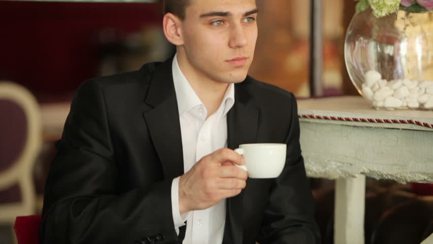 Businessman with a cup of coffee in hand. He looking at camera