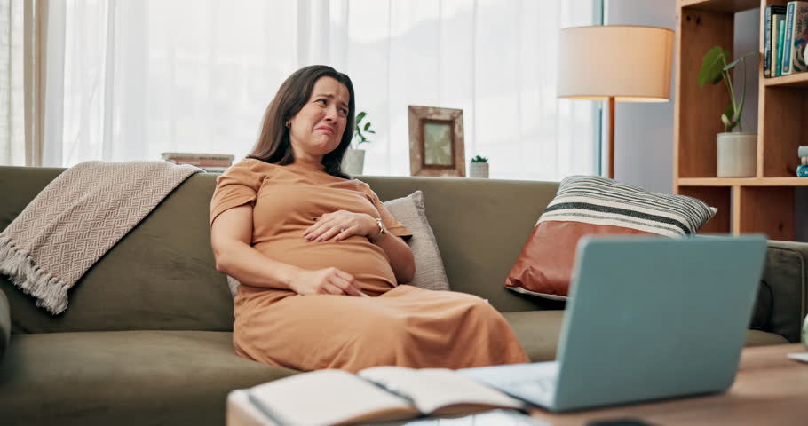 Crying, pregnancy and laptop with woman on sofa for streaming, sad or maternity health. Mood swings, tears and online show with mother and tissue in living room of family home for prenatal depression