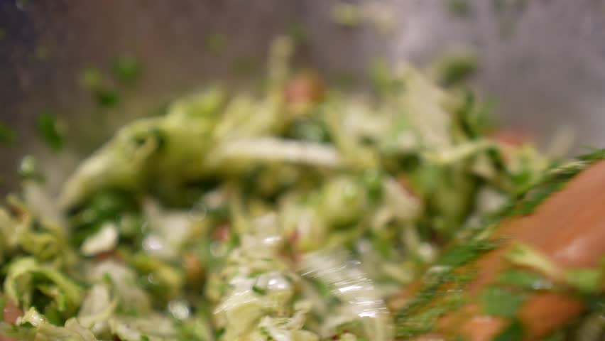 Close up of mixing salad with wooden spoon. Healthy food concept footage. Salad made of various vegetables. Vitamin source food. Mixing salad with lemon, olive oil and salt dressing.