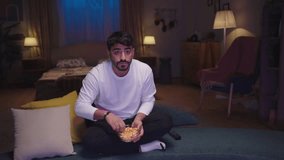 A man sits at home, eating popcorn and deeply focused on the TV, completely immersed in what he’s watching.
 - Powered by Shutterstock - Get 15% off with code: PIKWIZARD15