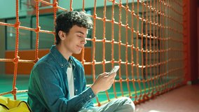 Smiling laughing positive Caucasian man male teenager guy teen student teenage pupil browsing cellphone modern technology playing game watching video funny using mobile phone smartphone app in school - Powered by Shutterstock - Get 15% off with code: PIKWIZARD15